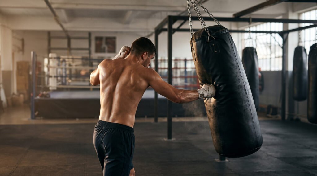 Boxeador golpeando un saco de boxeo colgante sujeto a una cadena en el techo